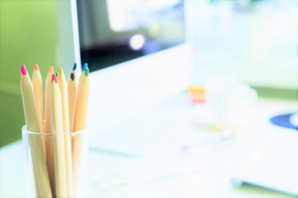 Colored pencils on a desk beside a computer
